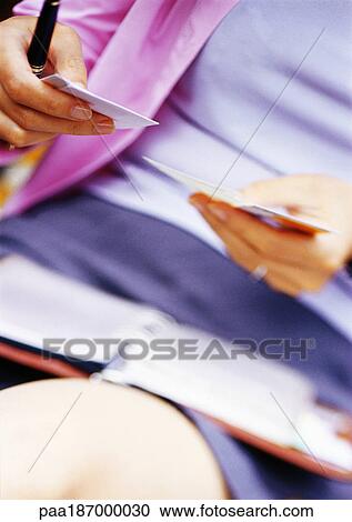 Stock Image - Businesswoman with agenda on lap, mid-section, close-up. Fotosearch