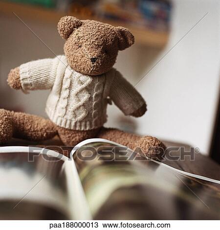 Stock Image - Stuffed teddy bear looking at book.. Fotosearch