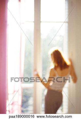 Stock Photograph - Woman looking out of window, rear view, three quarter length, blurred.. Fotosearch