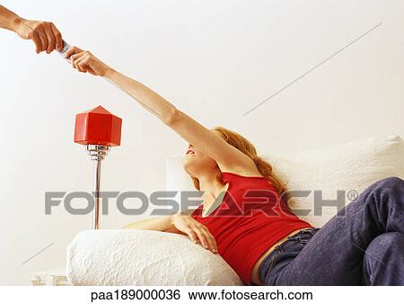 Woman on couch handing remote to someone. View Large Photo Image Stock Photograph - Woman on couch handing remote to someone.. Fotosearch