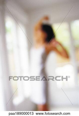 Stock Image - Woman stretching in front of window, blurred.. Fotosearch