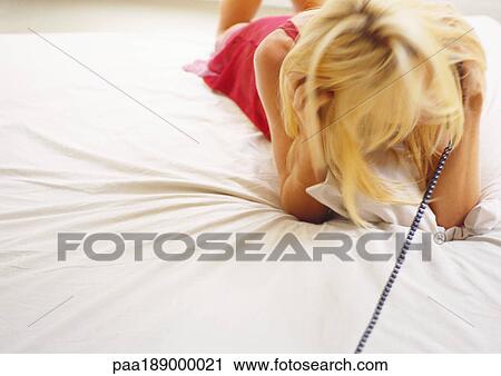 Woman talking on phone while lying on bed. View Large Photo Image Stock Image - Woman talking on phone while lying on bed.. Fotosearch