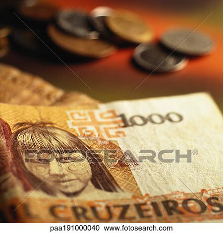Stock Image - Brazilian paper money near pile of coins.. Fotosearch