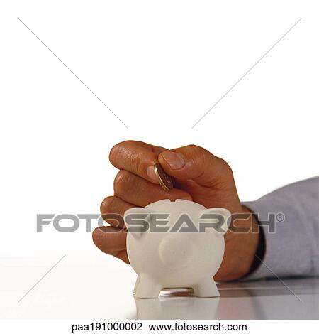 Stock Image - Hand dropping a coin in a piggy bank.. Fotosearch