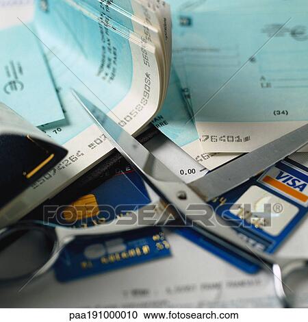 Stock Image - Scissors with cut credit card and checks.. Fotosearch