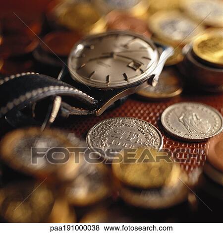 Wristwatch on top of assorted coins. View Large Photo Image Stock Photo - Wristwatch on top of assorted coins.. Fotosearch