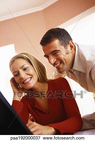 Stock Photo - Man looking over shoulder of woman using computer.. Fotosearch