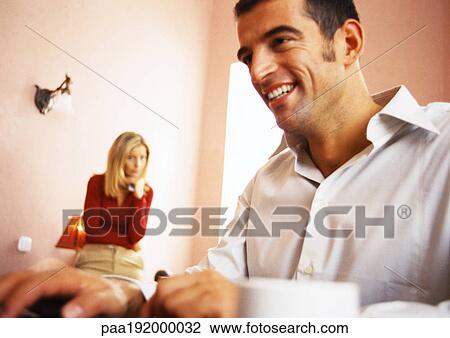 Man smiling, woman watching in background. View Large Photo Image Stock Image - Man smiling, woman watching in background.. Fotosearch