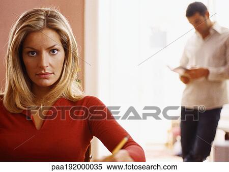 Woman looking at camera, man standing in background. View Large Photo Image Stock Photography - Woman looking at camera, man standing in background.. Fotosearch