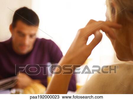 Stock Image - Woman sitting across from man at table, rear view.. Fotosearch