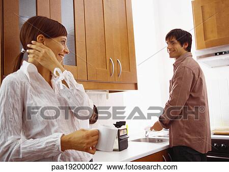 Woman smiling at man washing dishes. View Large Photo Image Stock Photo - Woman smiling at man washing dishes.. Fotosearch