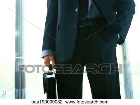 Businessman holding briefcase, hand in pocket, mid-section View Large Photo Image Stock Image - Businessman holding briefcase, hand in pocket, mid-section. Fotosearch
