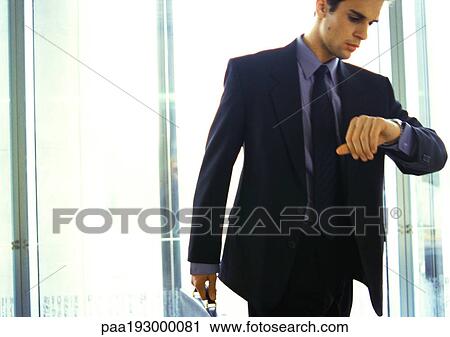 Stock Image - Businessman looking at watch.. Fotosearch
