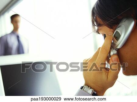 Businessman on cell phone facing computer, side view, close-up View Large Photo Image Stock Photo - Businessman on cell phone facing computer, side view, close-up. Fotosearch