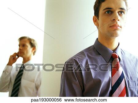 Businessman on cell phone near businessman standing. View Large Photo Image Stock Photograph - Businessman on cell phone near businessman standing.. Fotosearch