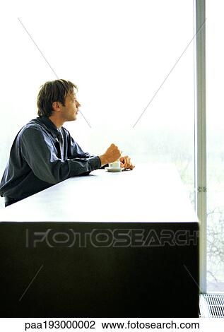 Businessman sitting at desk with coffee, looking out of window. View Large Photo Image Stock Image - Businessman sitting at desk with coffee, looking out of window.. Fotosearch