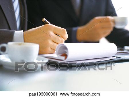 Businessman writing near businessman holding cup. View Large Photo Image Stock Image - Businessman writing near businessman holding cup.. Fotosearch