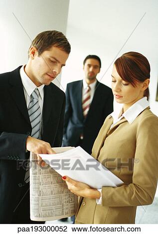 Businesspeople, two in foreground looking at document View Large Photo Image Stock Image - Businesspeople, two in foreground looking at document. Fotosearch