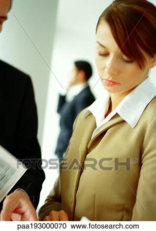 Businesswoman next to businessman, looking down, second man in background View Large Photo Image Stock Image - Businesswoman next to businessman, looking down, second man in background. Fotosearch