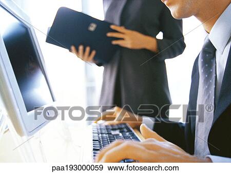 Businesswoman standing near businessman using computer, partial view. View Large Photo Image Stock Photo - Businesswoman standing near businessman using computer, partial view.. Fotosearch