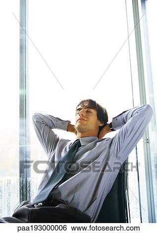 Man leaning back in chair, hands behind head View Large Photo Image Stock Photograph - Man leaning back in chair, hands behind head. Fotosearch