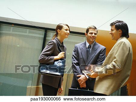 Three businesspeople standing and talking View Large Photo Image Stock Photograph - Three businesspeople standing and talking. Fotosearch