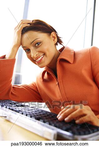 Woman at keyboard, smiling at camera. View Large Photo Image Stock Photograph - Woman at keyboard, smiling at camera.. Fotosearch