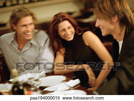 Group of young people sitting at table, having dinner together View Large Photo Image Stock Photography - Group of young people sitting at table, having dinner together. Fotosearch
