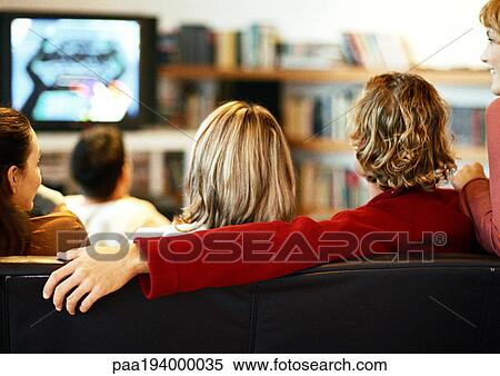 People sitting on couch watching TV, rear view. View Large Photo Image Stock Photography - People sitting on couch watching TV, rear view.. Fotosearch