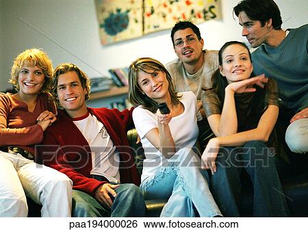 People sitting together on couch, one woman holding remote. View Large Photo Image Stock Photograph - People sitting together on couch, one woman holding remote.. Fotosearch