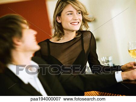 Stock Photo - Young man and woman at bar, smiling. Fotosearch