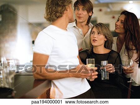 Stock Image - Young men and women drinking at bar. Fotosearch