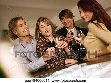 Young men and women drinking at bar View Large Photo Image Stock Image - Young men and women drinking at bar. Fotosearch
