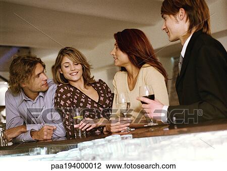 Young men and women drinking at bar View Large Photo Image Stock Image - Young men and women drinking at bar. Fotosearch