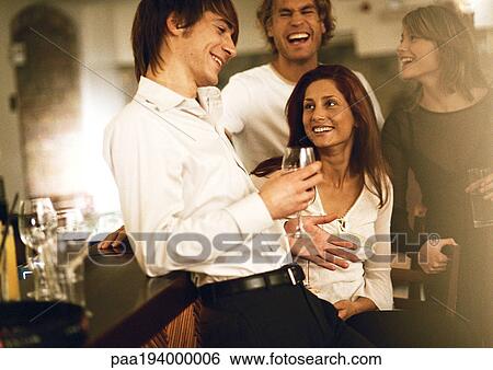 Young men and women drinking at bar View Large Photo Image Stock Photograph - Young men and women drinking at bar. Fotosearch