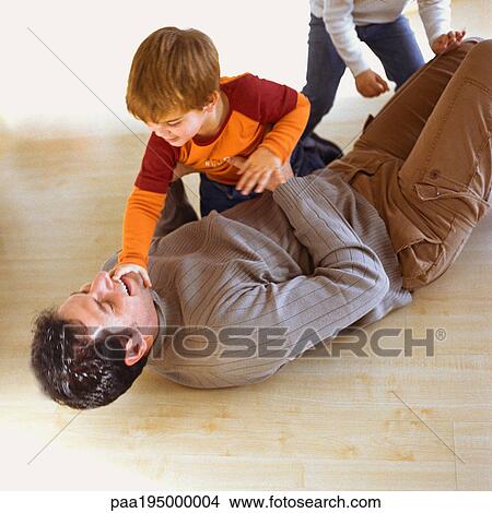 Picture - Children playing with father on the floor. Fotosearch