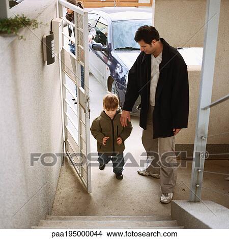 Father coming in door with with son, full length, high angle view View Large Photo Image Picture - Father coming in door with with son, full length, high angle view. Fotosearch