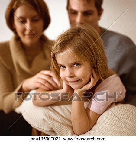 Little girl looking at camera, parents behind her. View Large Photo Image Stock Image - Little girl looking at camera, parents behind her.. Fotosearch