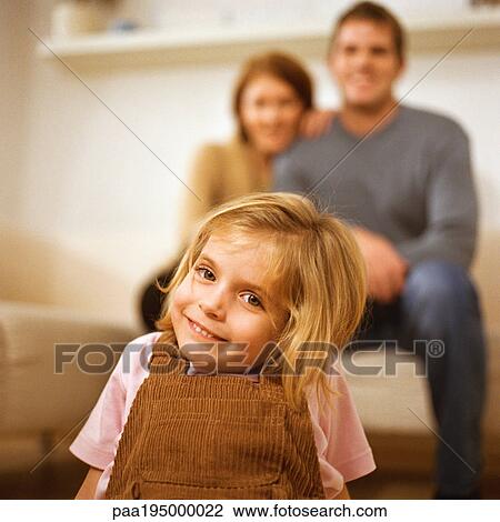 Little girl smiling at camera, parents behind her. View Large Photo Image Stock Image - Little girl smiling at camera, parents behind her.. Fotosearch