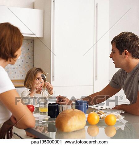 Stock Image - Mother and father with daughter at breakfast table.. Fotosearch