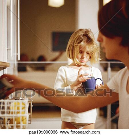 Mother loading dishwasher, daughter holding mug View Large Photo Image Stock Photograph - Mother loading dishwasher, daughter holding mug. Fotosearch