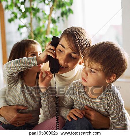 Mother sitting with children, daughter holding phone to mother's ear. View Large Photo Image Stock Photography - Mother sitting with children, daughter holding phone to mother's ear.. Fotosearch
