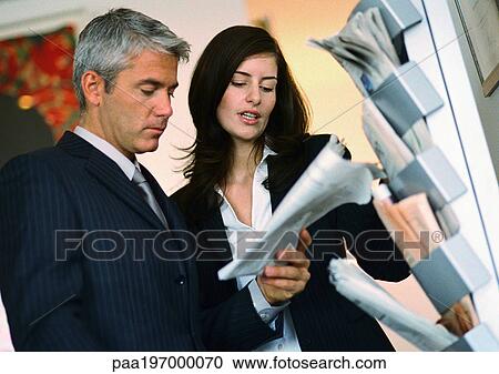 Businessman and businesswoman looking at newspaper. View Large Photo Image Stock Image - Businessman and businesswoman looking at newspaper.. Fotosearch