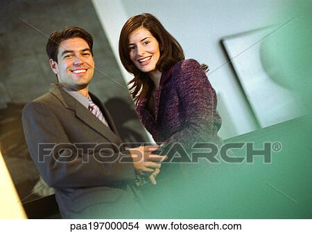 Businessman holding businesswoman's hand, smiling at camera. View Large Photo Image Picture - Businessman holding businesswoman's hand, smiling at camera.. Fotosearch