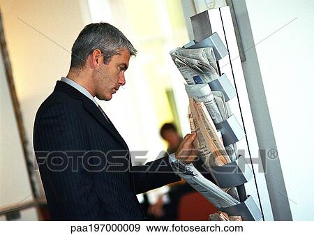 Businessman looking at newspapers on wall rack. View Large Photo Image Stock Photo - Businessman looking at newspapers on wall rack.. Fotosearch