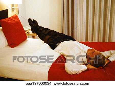Businessman lying across bed. View Large Photo Image Picture - Businessman lying across bed.. Fotosearch