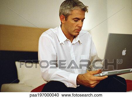 Businessman sitting on bed using laptop. View Large Photo Image Stock Image - Businessman sitting on bed using laptop.. Fotosearch