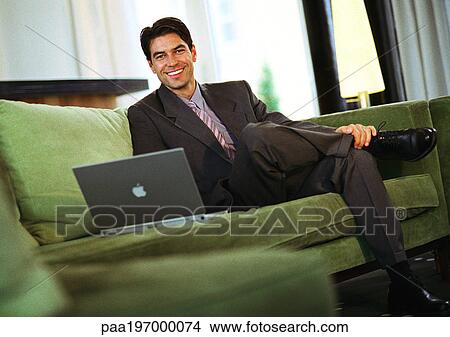 Businessman sitting on couch smiling at camera View Large Photo Image Picture - Businessman sitting on couch smiling at camera. Fotosearch