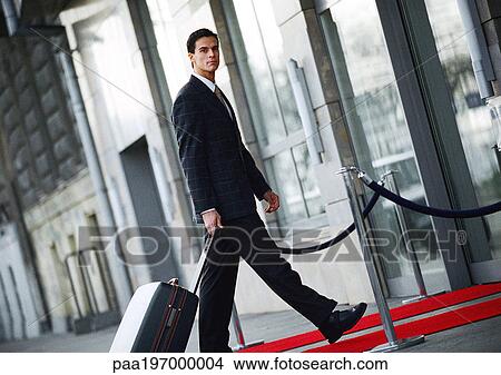 Picture - Businessman walking with luggage outside, side view.. Fotosearch