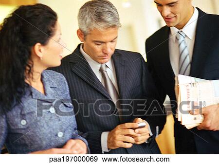Businessmen and businesswoman, one holding cell phone. View Large Photo Image Stock Photo - Businessmen and businesswoman, one holding cell phone.. Fotosearch